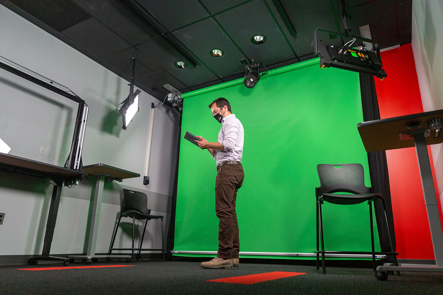 A user in the video studio in front of a green screen, using the wireless controls
