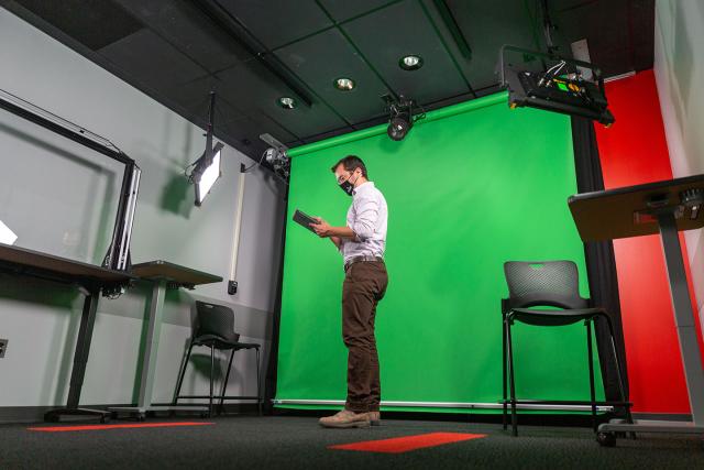 A user in the video studio in front of a green screen, using the wireless controls